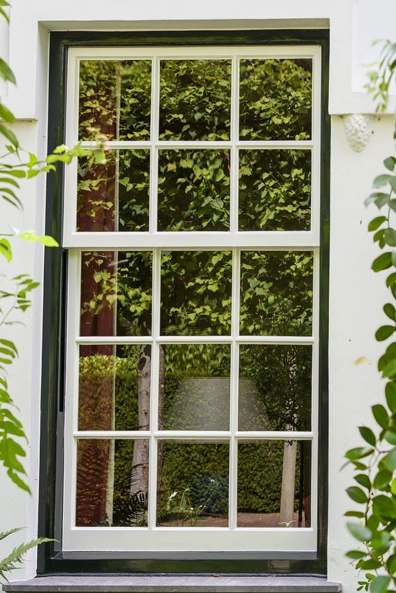 Houten raam met roedeverdeling, omgeven door groen