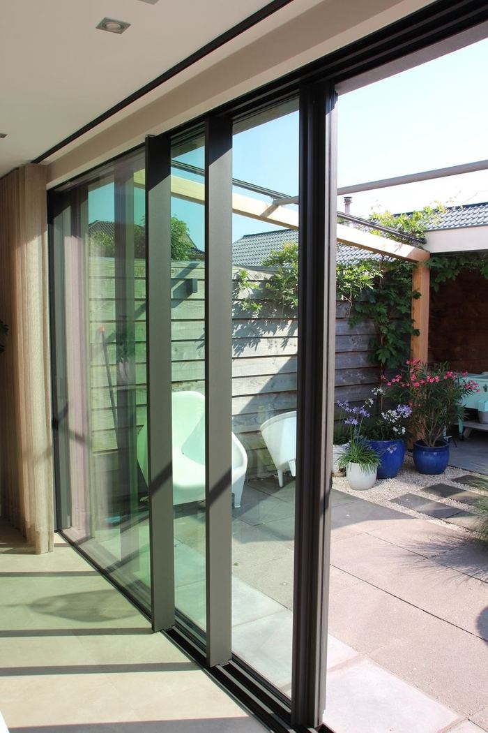 Detailopname van het schuifsysteem van een aluminium schuifpui, met zicht op het terras